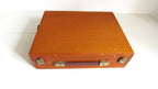 A vintage wooden art  box with a warm orange-brown finish, featuring brass latches and a dark handle, photographed on a white background.