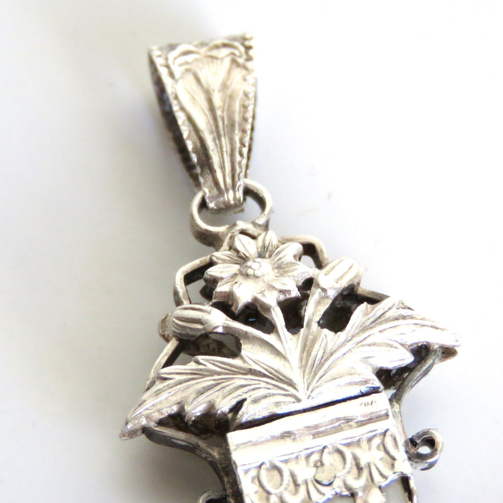 Silver pendant with floral design on a white background