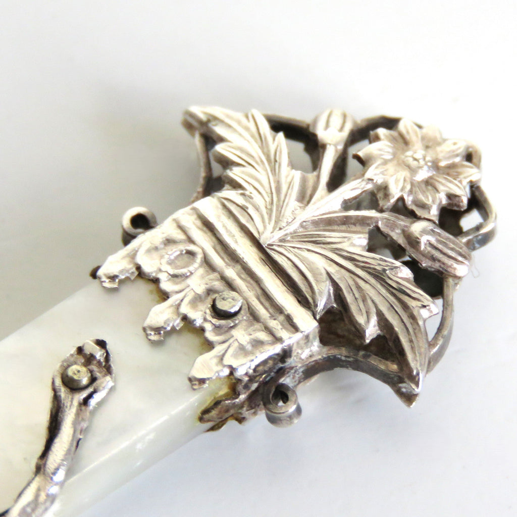 Decorative silver tip with floral design on a white background