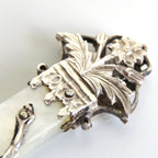 Decorative silver tip with floral design on a white background