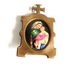 An antique  brass  frame featuring  an oval inset  Madonna della Saggiola by Raphael set against a plain white background.