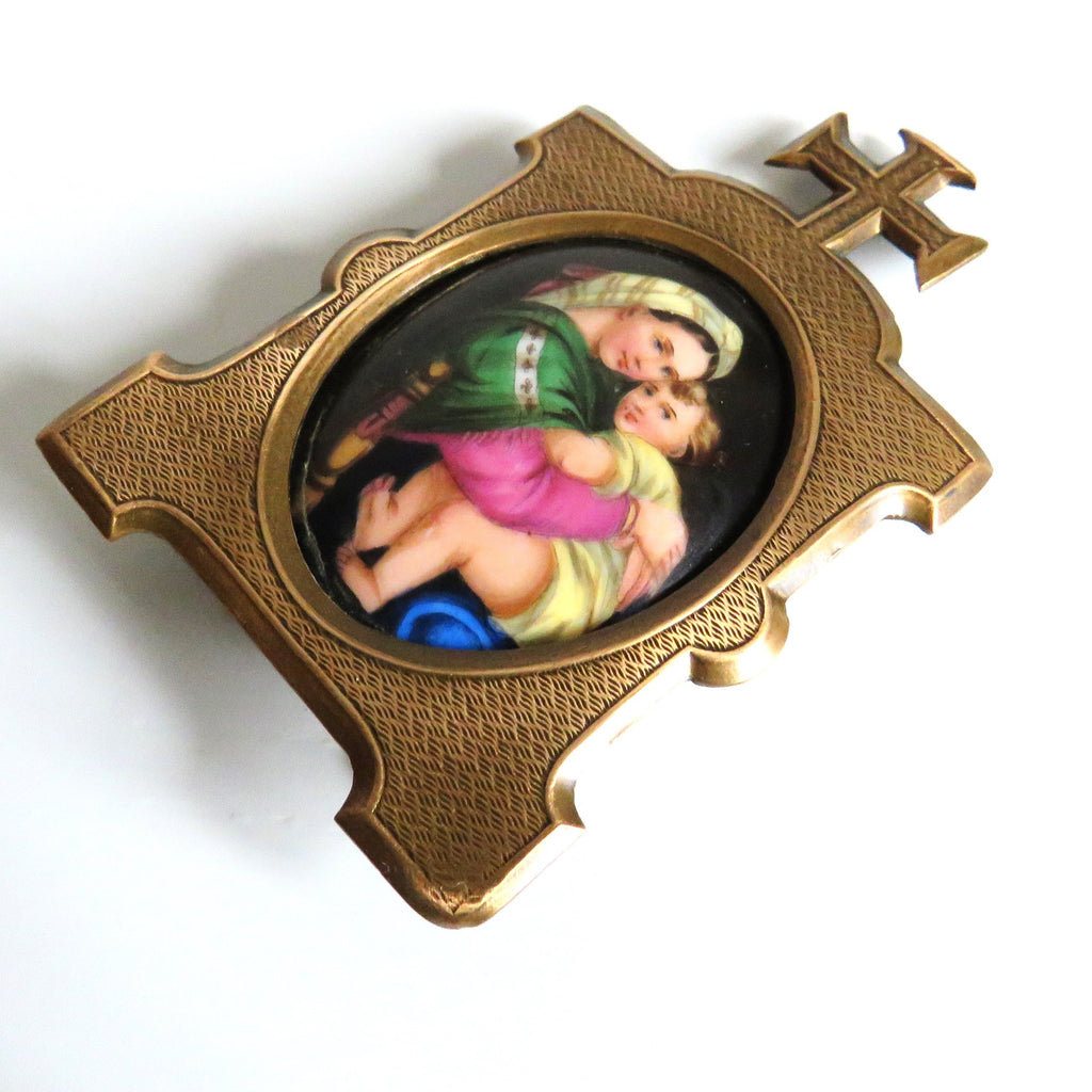 A vintage brass  frame featuring  an oval inset  Madonna della Saggiola by Raphael set against a plain white background.