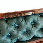 Close-up of a vintage leather chest  with a teal green tufted silk 
front and a brass latch.